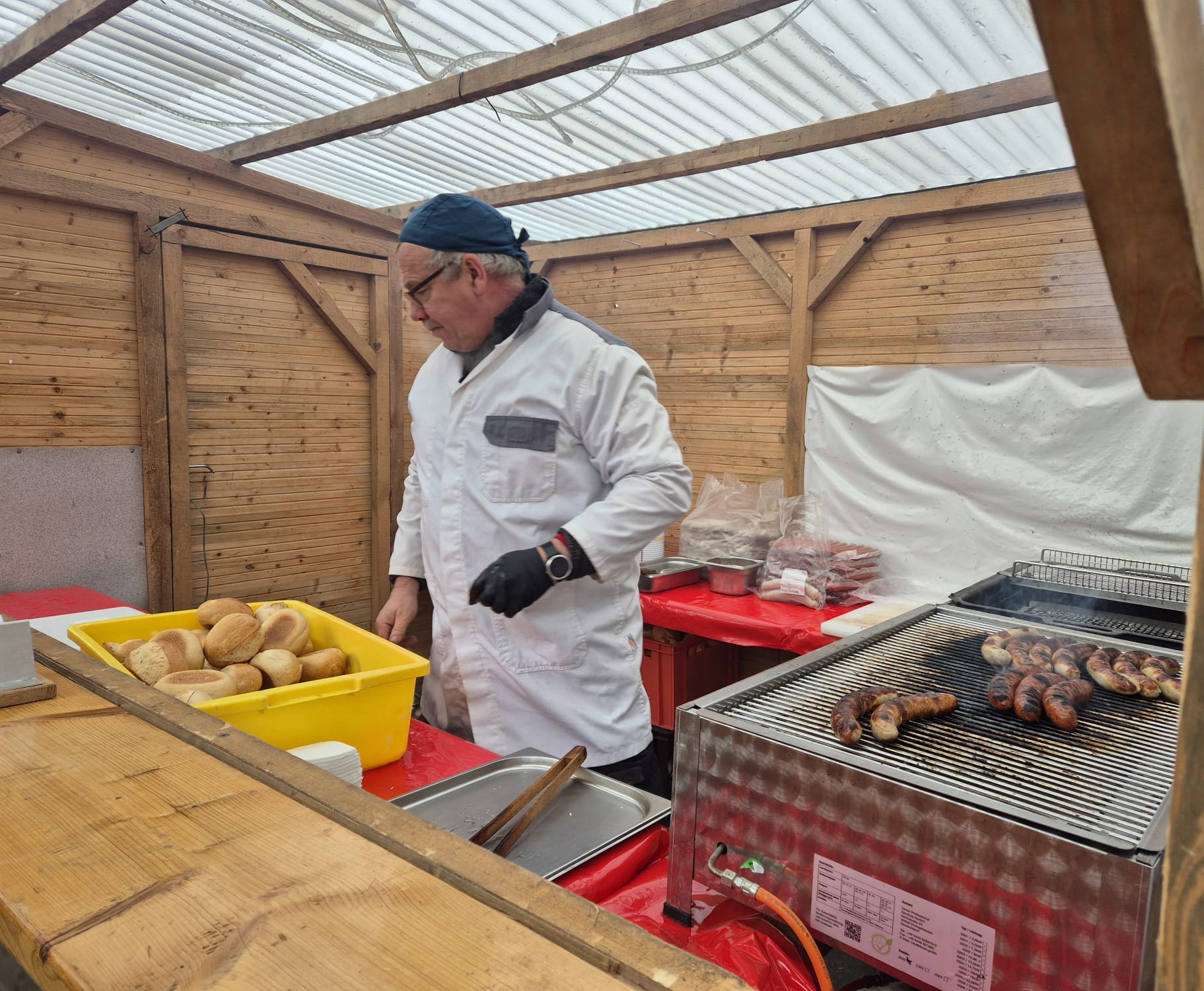 Mitarbeiter am Grill mit frischen Bratwürsten und Brötchen
